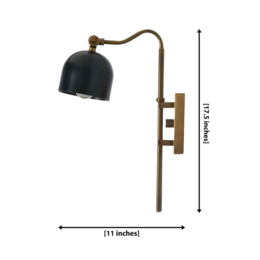 Brass patina bathroom vanity sconce with black dome shade mounted beside a mirror for warm accent lighting