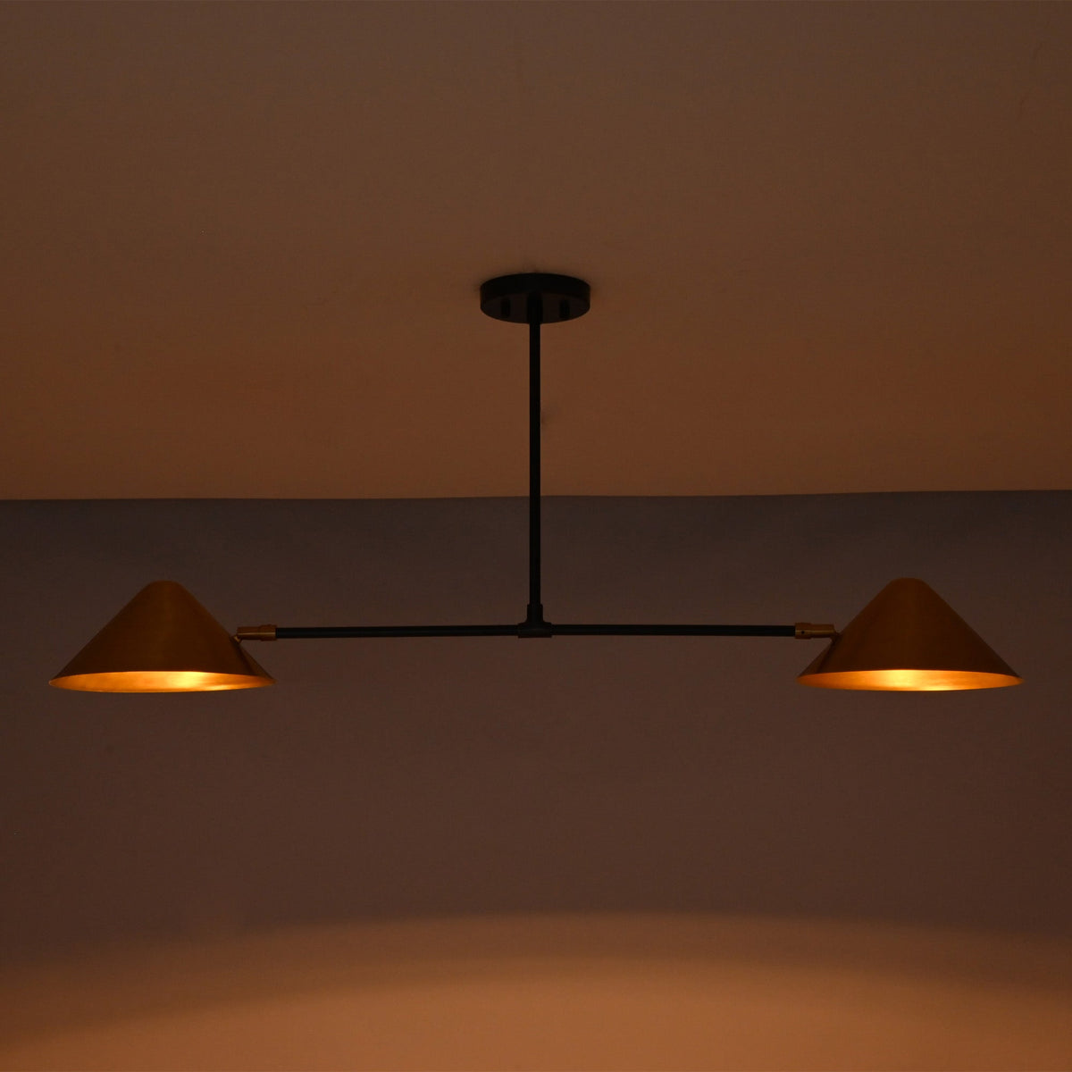 Oslo Modern Double Cone Linear Chandelier with warm illuminated cone shades in low-light setting