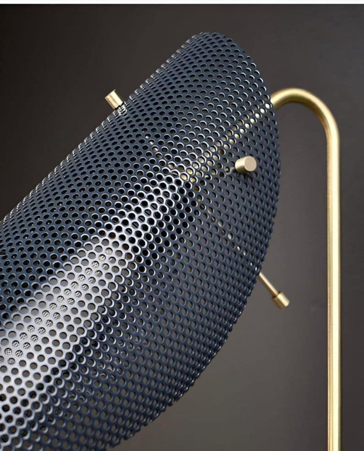 Close-up of perforated metal shade on handcrafted brass wall lamp showing fine detailing