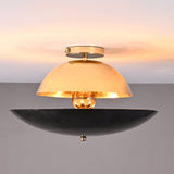 Front view of mixed-finish brass flushmount light with polished brass dome and blackened lower bowl, creating warm indirect illumination.