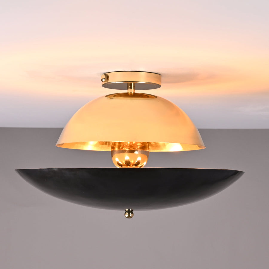 Front view of mixed-finish brass flushmount light with polished brass dome and blackened lower bowl, creating warm indirect illumination.