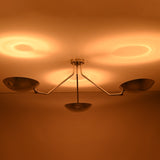 Three light polished chrome ceiling fixture highlighting symmetrical bowl shaped shades and warm glow.