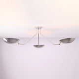 Angled view of polished chrome semi flush mount ceiling light featuring three sculpted brass bowl shades.