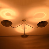 Polished chrome ceiling light casting warm indirect ambient lighting through three brass bowl shades.