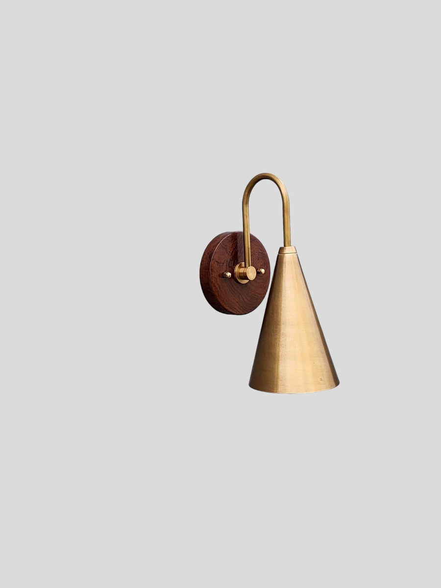 Side view of modern brass and wood wall sconce handcrafted by Brass Leaf Studio with cone-shaped brass shade and round wooden base.