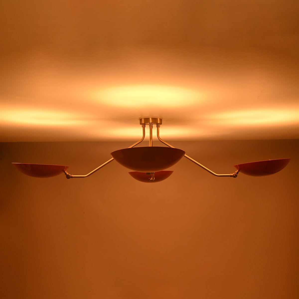 Flush mount red disc chandelier producing soft ambient glow with bowl shaped shades and premium brass construction.
