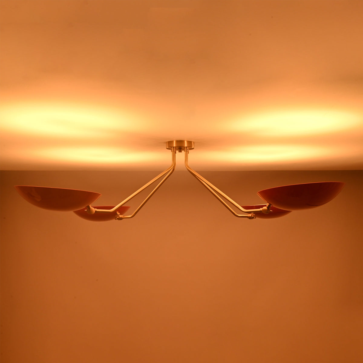 Top view of red disc flush mount ceiling light when lit, showcasing soft uplighting and balanced four light configuration.
