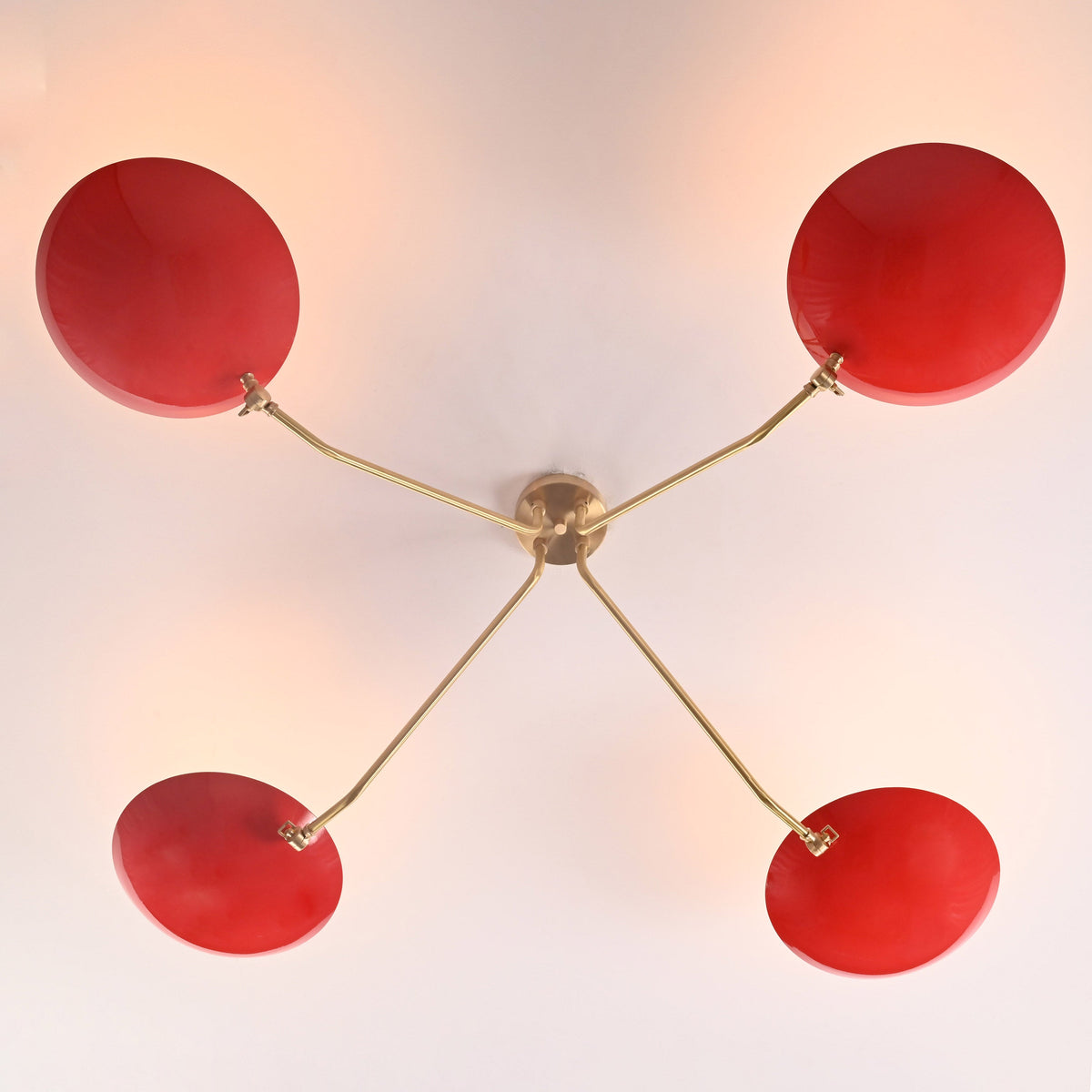 Top view of modern red disc flush mount chandelier featuring four bowl shades and sculpted solid brass arms in symmetrical layout.