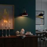 Close-up of red bowl shade brass wall sconce showing smooth glossy finish, round canopy, and warm light output