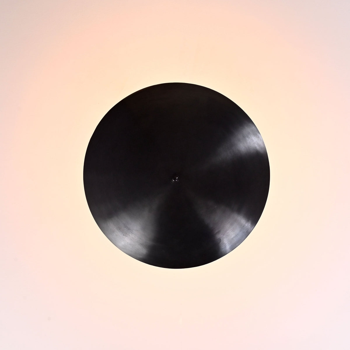 Top view of blackened brass bowl ceiling light showing circular uplight pattern