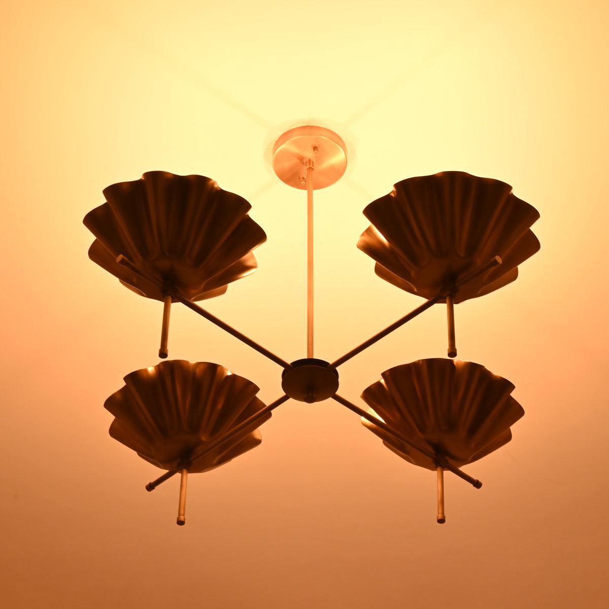 Bottom view of brass bowl chandelier with warm ambient lighting and symmetrical shell shade layout