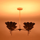 Side view of brass shell shade chandelier illuminated in low light for atmospheric effect
