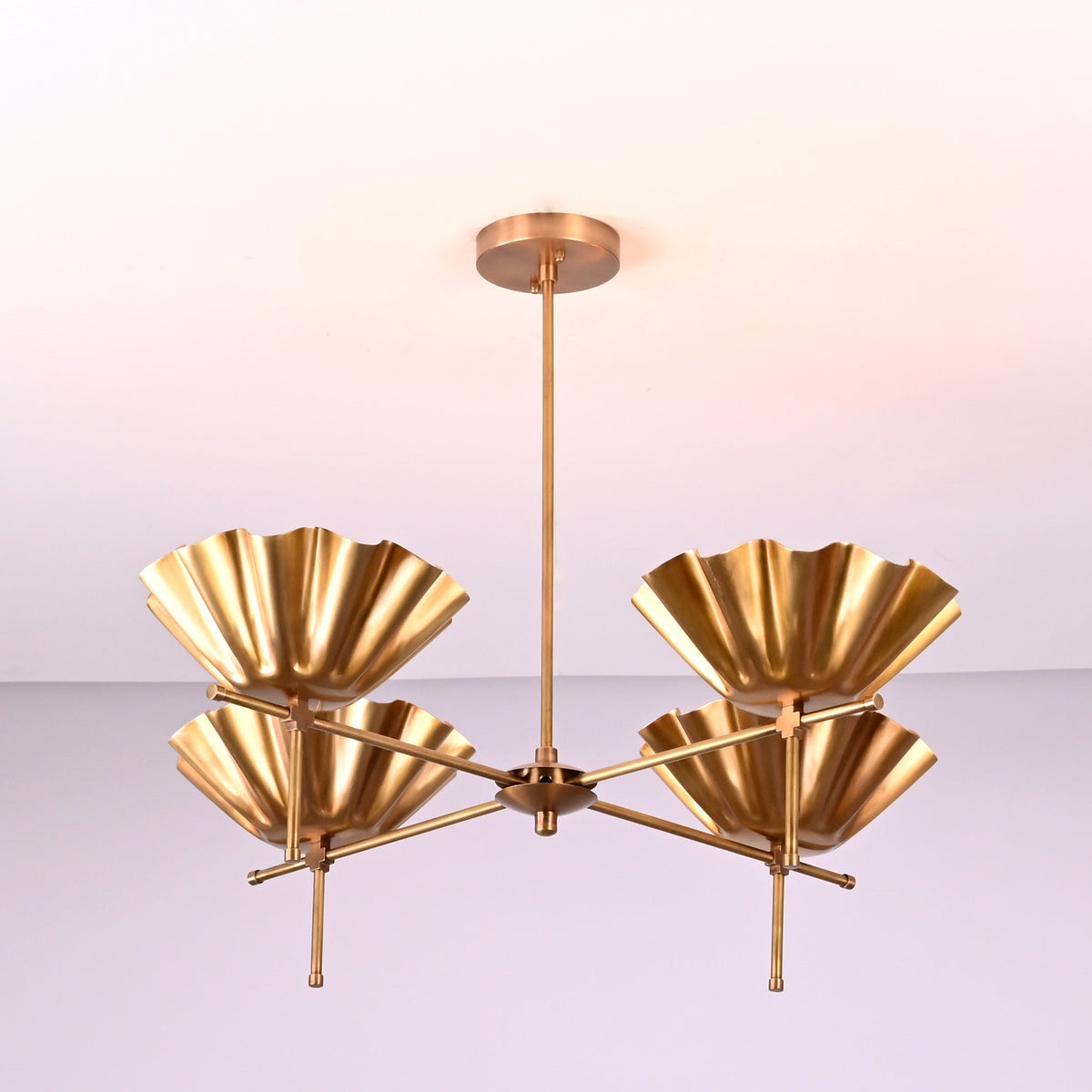 Side angle view of modern brass chandelier with fluted bowl shades and solid brass construction