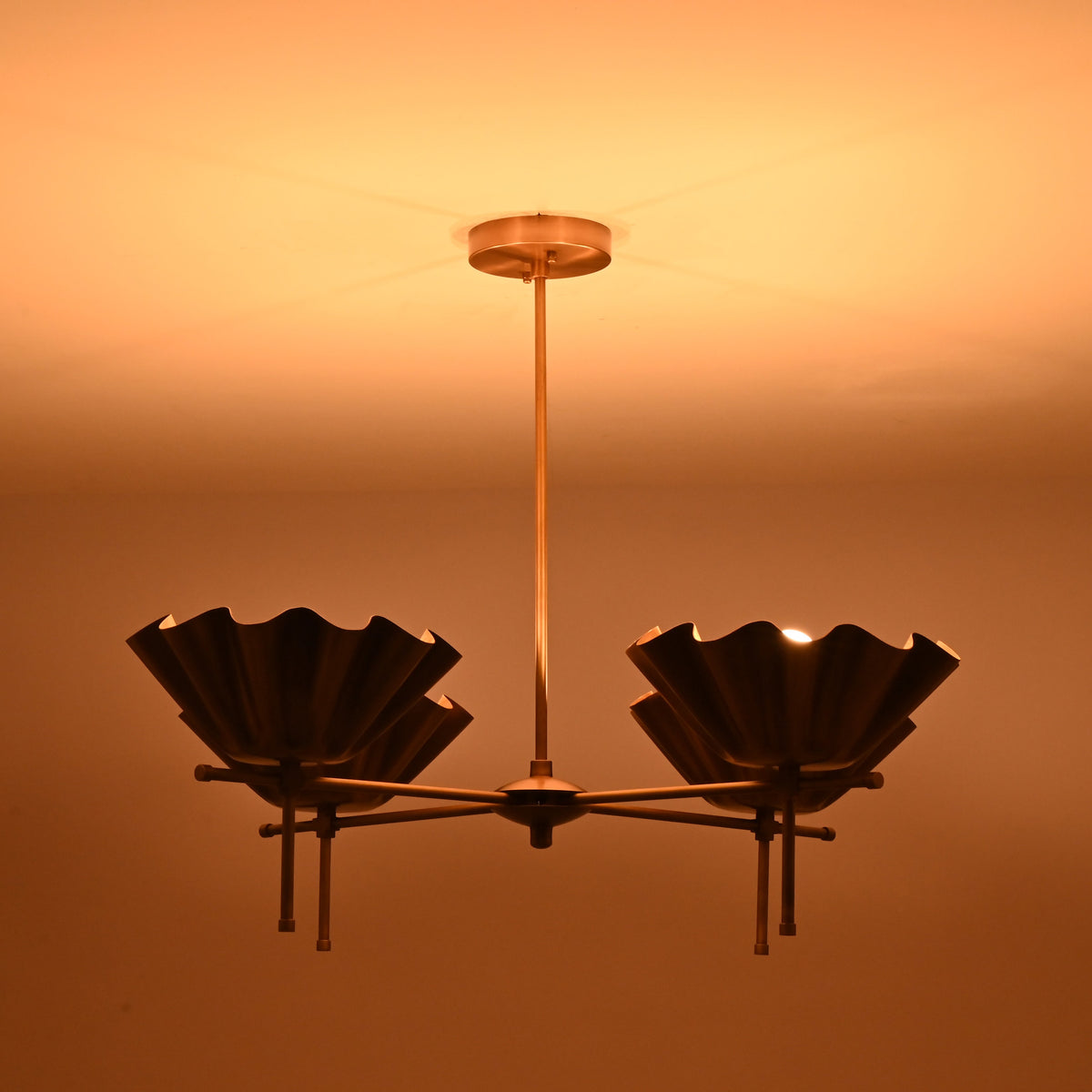 Brass scalloped bowl chandelier glowing warmly in a dark room creating soft ambient light