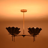 Brass scalloped bowl chandelier glowing warmly in a dark room creating soft ambient light