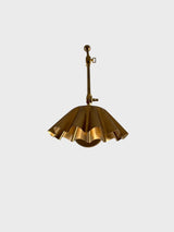 Bottom view of scalloped brass shade on swing arm wall lamp, showing curved edge detailing.