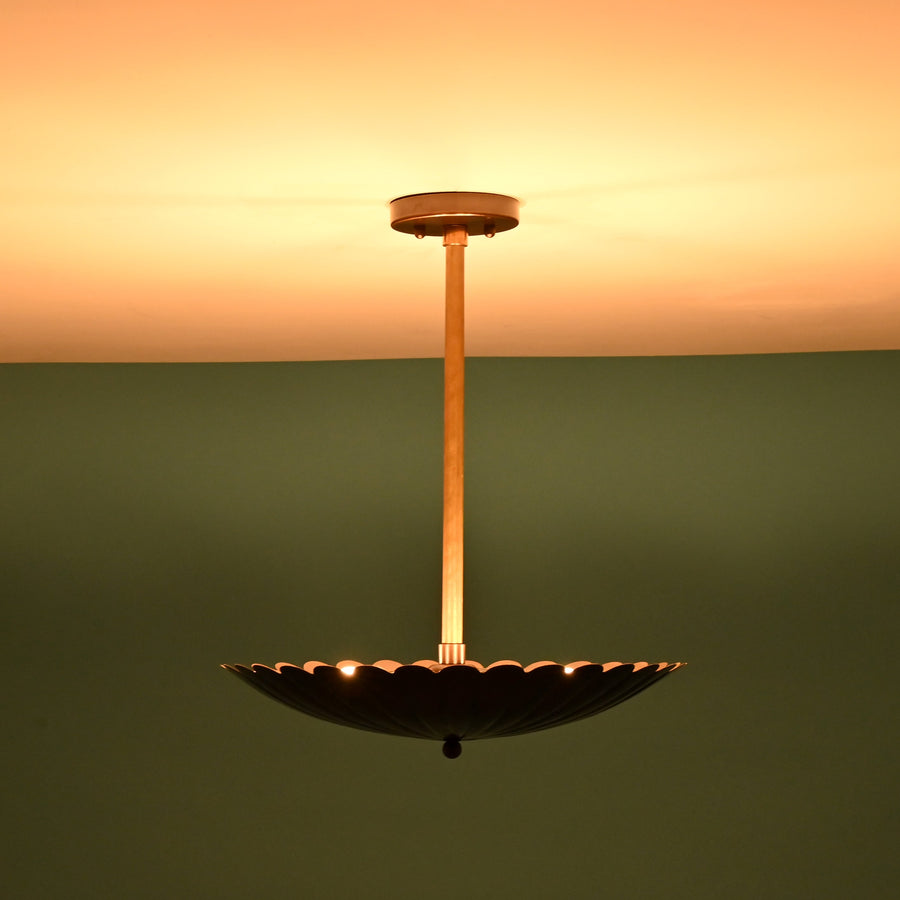 Side angle view of handcrafted scalloped brass pendant light with pleated disc shade