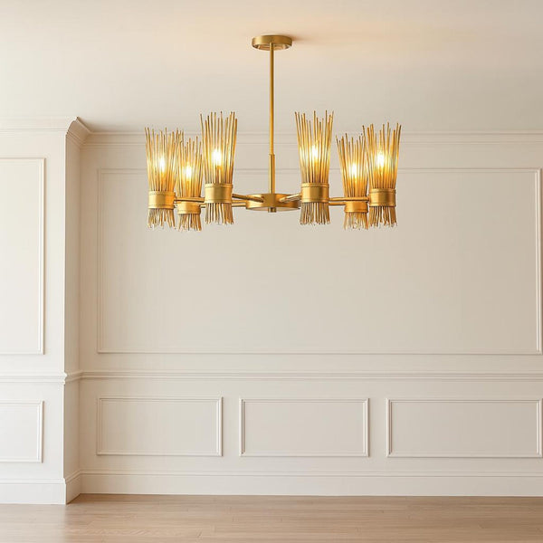 Six light sculpted brass reed chandelier in brushed brass finish hanging in a minimalist interior, showcasing warm ambient lighting and handcrafted metal detailing.