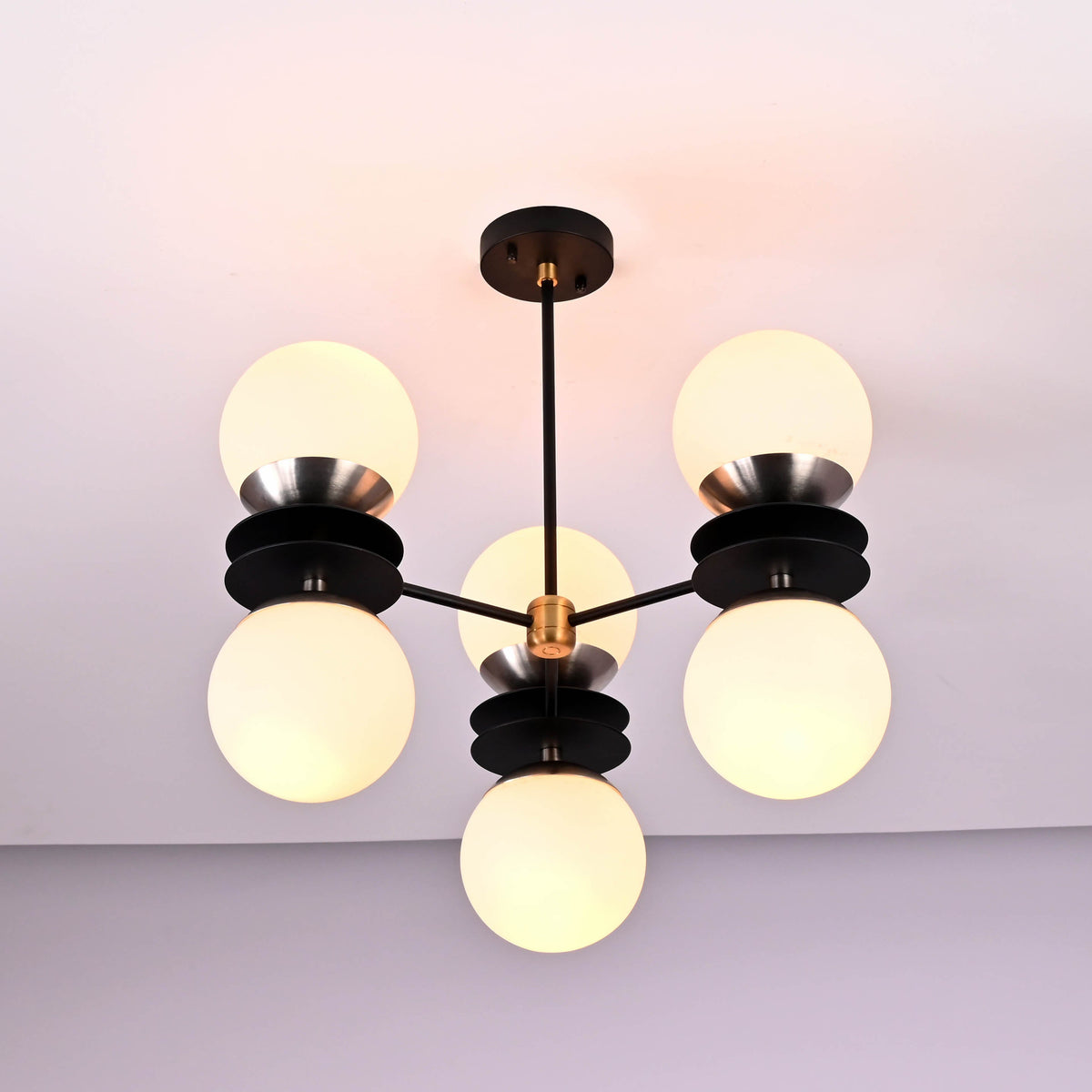 Close view of sculptural brass disc chandelier detailing opal glass globes and solid brass craftsmanship