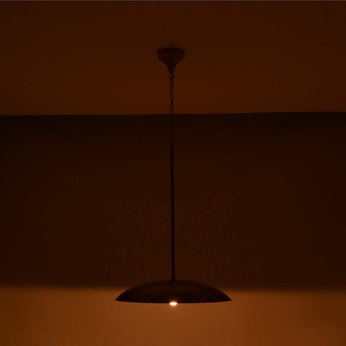 Shallow dome ceiling pendant light with slim suspension rod, chain detail, and warm ambient downward illumination