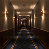 Slotted brass tube sconce side view showing solid brass construction, round wall canopy, and soft ambient light effect