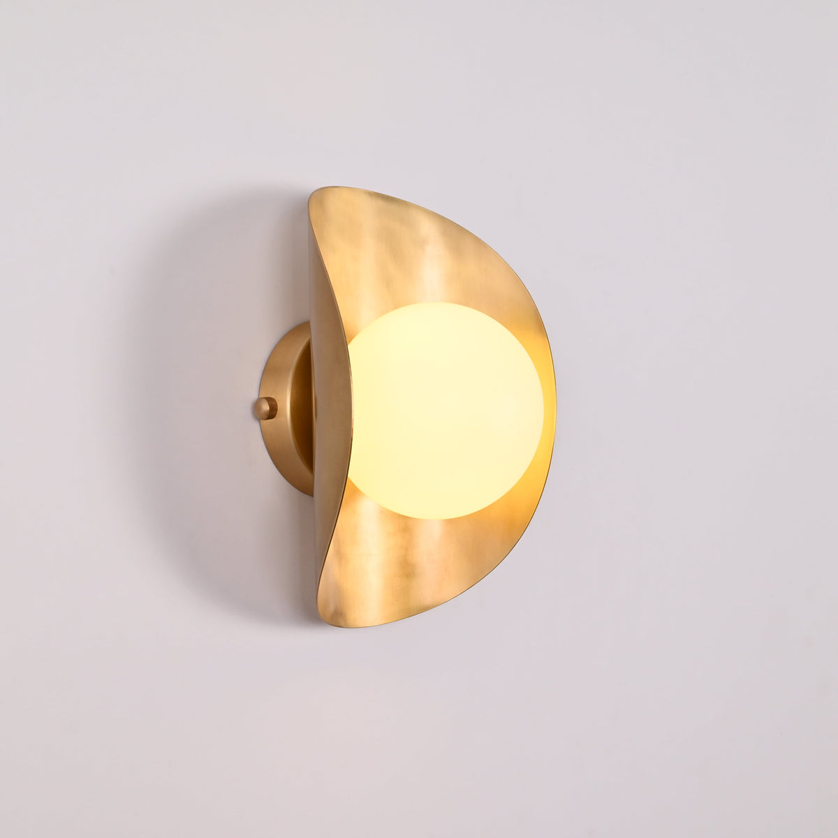 Solara globe wall light closeup showing warm diffused globe and sculptural crescent shield