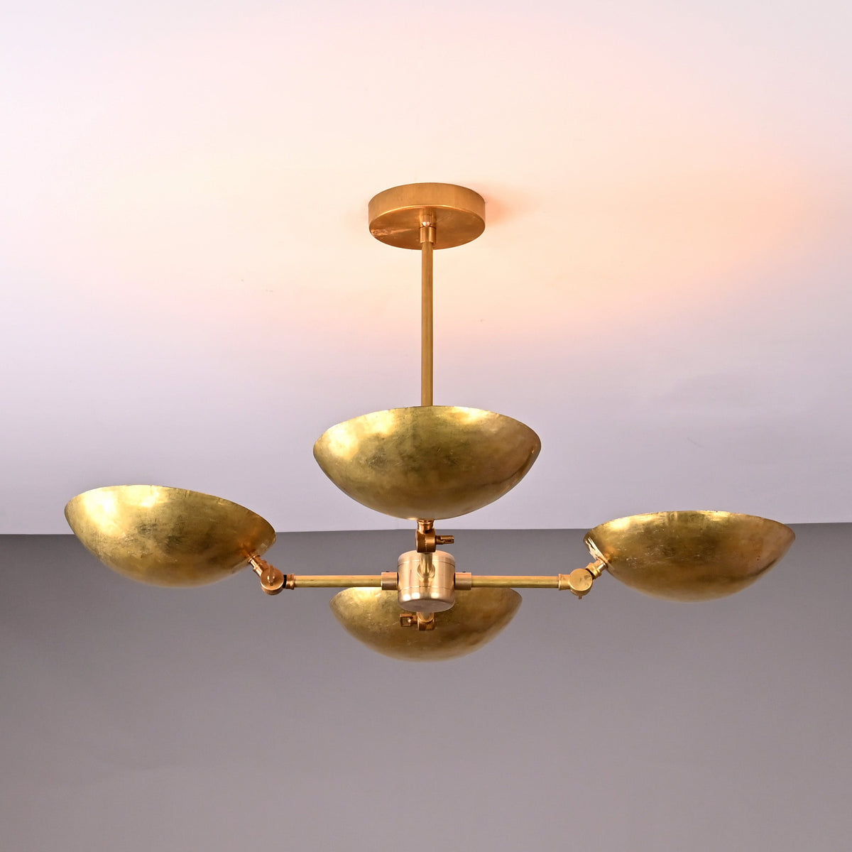 Top angled view of solid brass chandelier with four hammered bowl-shaped shades, highlighting craftsmanship and modern sculptural form.