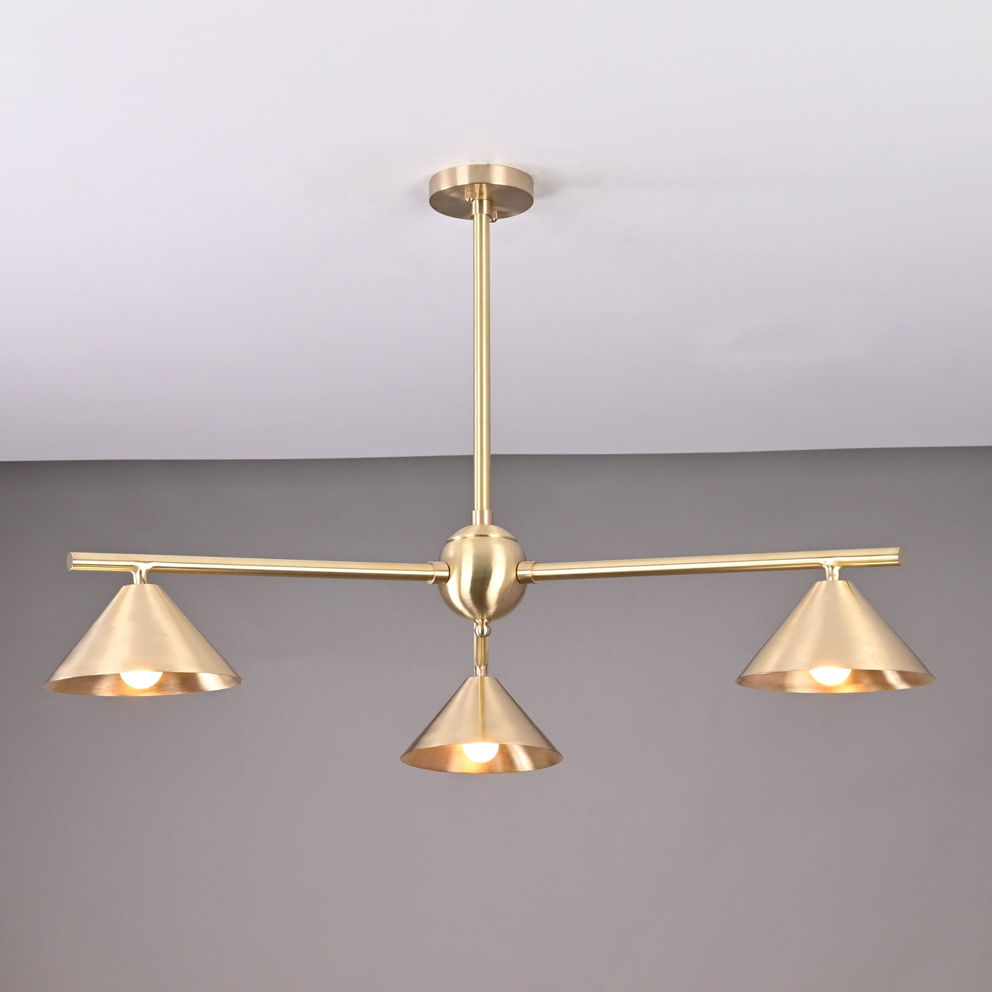 Modern solid brass chandelier with three cone-shaped shades, brushed finish, handcrafted for contemporary interior lighting.