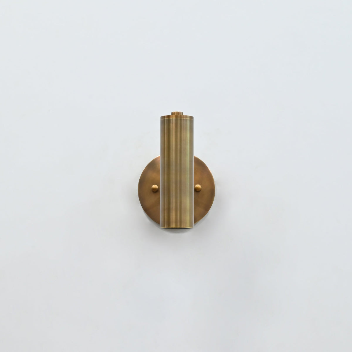 Solid brass cylinder wall light with focused downward glow, ideal for bedside reading and hallway lighting