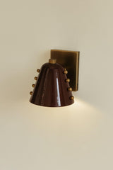 Close-up of solid brass wall sconce backplate with burgundy cone shade
