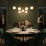 Sorrento brass wall sconce shown illuminated with warm ambient light from three glowing glass globes