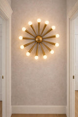 12-light starburst brass wall fixture mounted in a hallway, adding architectural interest with warm, indirect lighting.