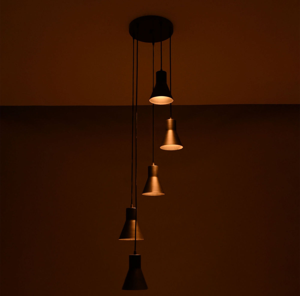 Close perspective of the Sutton Cascade Cone Multi Pendant Chandelier highlighting the warm glow and staggered five-light cascading design.