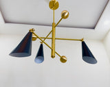 Low angle view of three cone brass chandelier highlighting solid brass arms, precision joints, and minimalist industrial design.