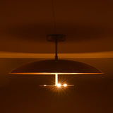 Three-light brass disc flushmount ceiling fixture glowing warmly in a dark interior