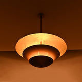 Tiered brass pendant light installed above a bedroom, creating soft warm ceiling light with elegant layered style