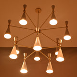 Closeup of two-tier white cone chandelier with warm downward glow and elegant brushed brass connecting arms