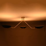 Night view of black and brass chandelier emitting soft golden ambient light across the ceiling.
