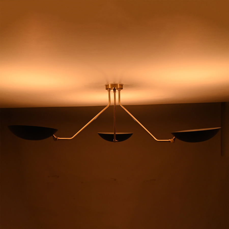 Front view of modern black and brass 3-light bowl chandelier with sculptural arms and matte black shades.