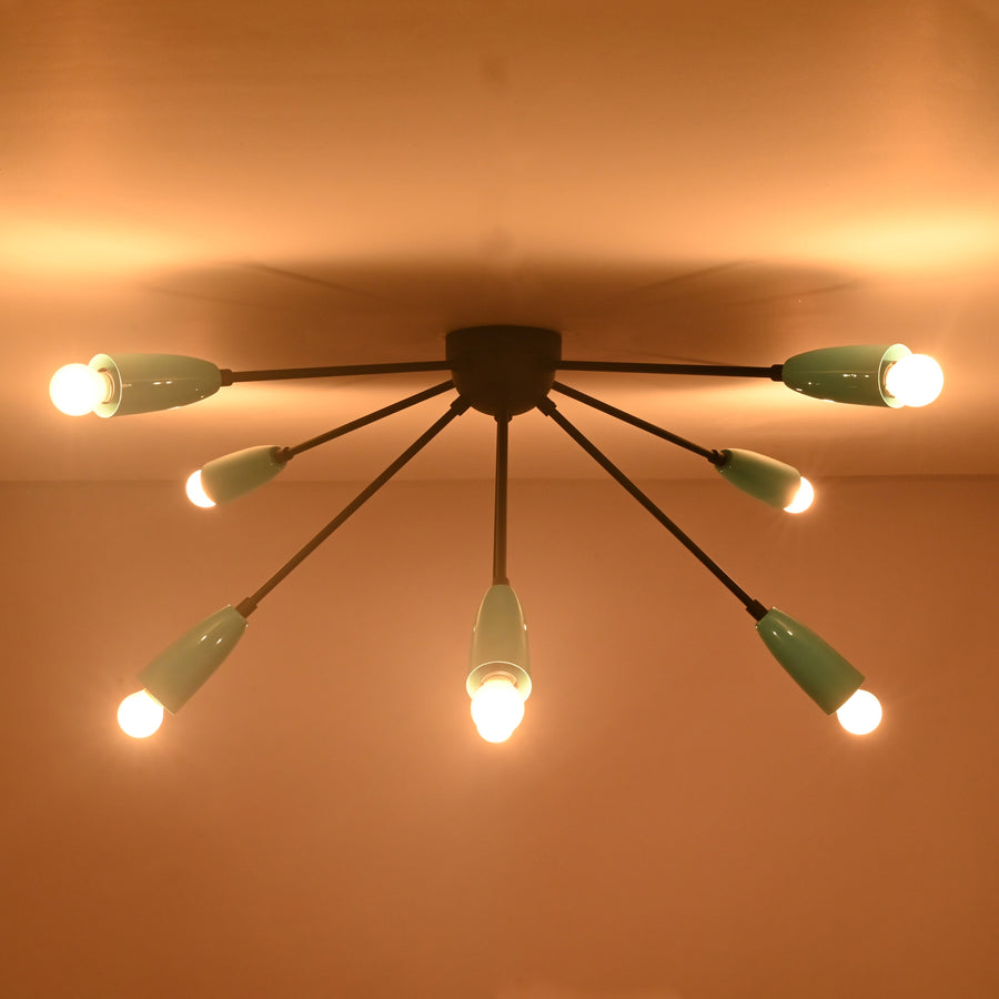 Modern orbit-style 8-light brass flush mount chandelier illuminated with warm ambient lighting